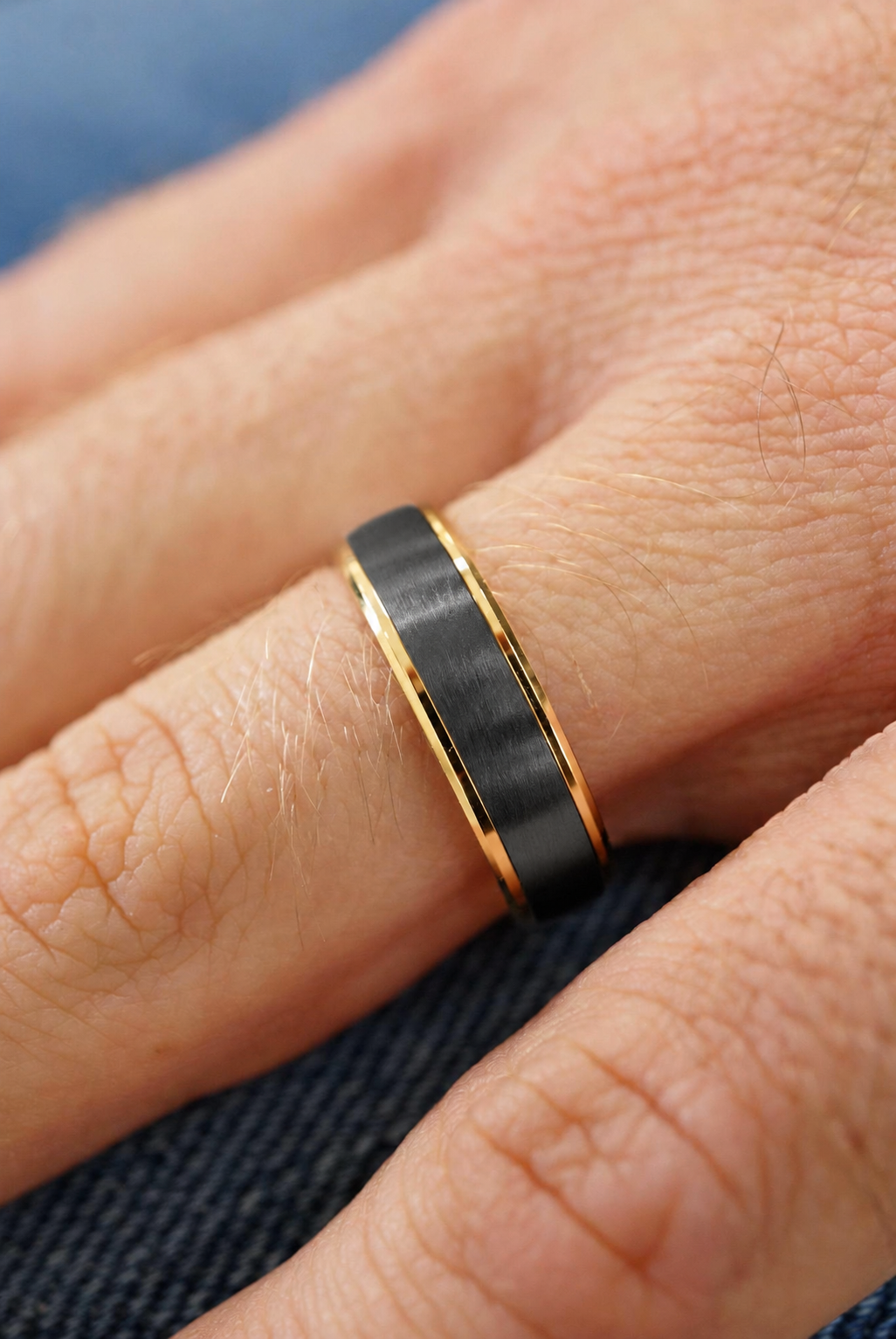 Close-up of Charcoal and Gold Step Edge Band worn on finger